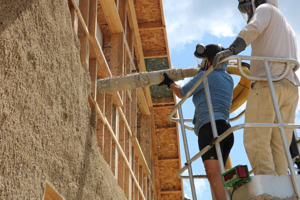 Construction workers installing hempcrete blocks into a wall frame